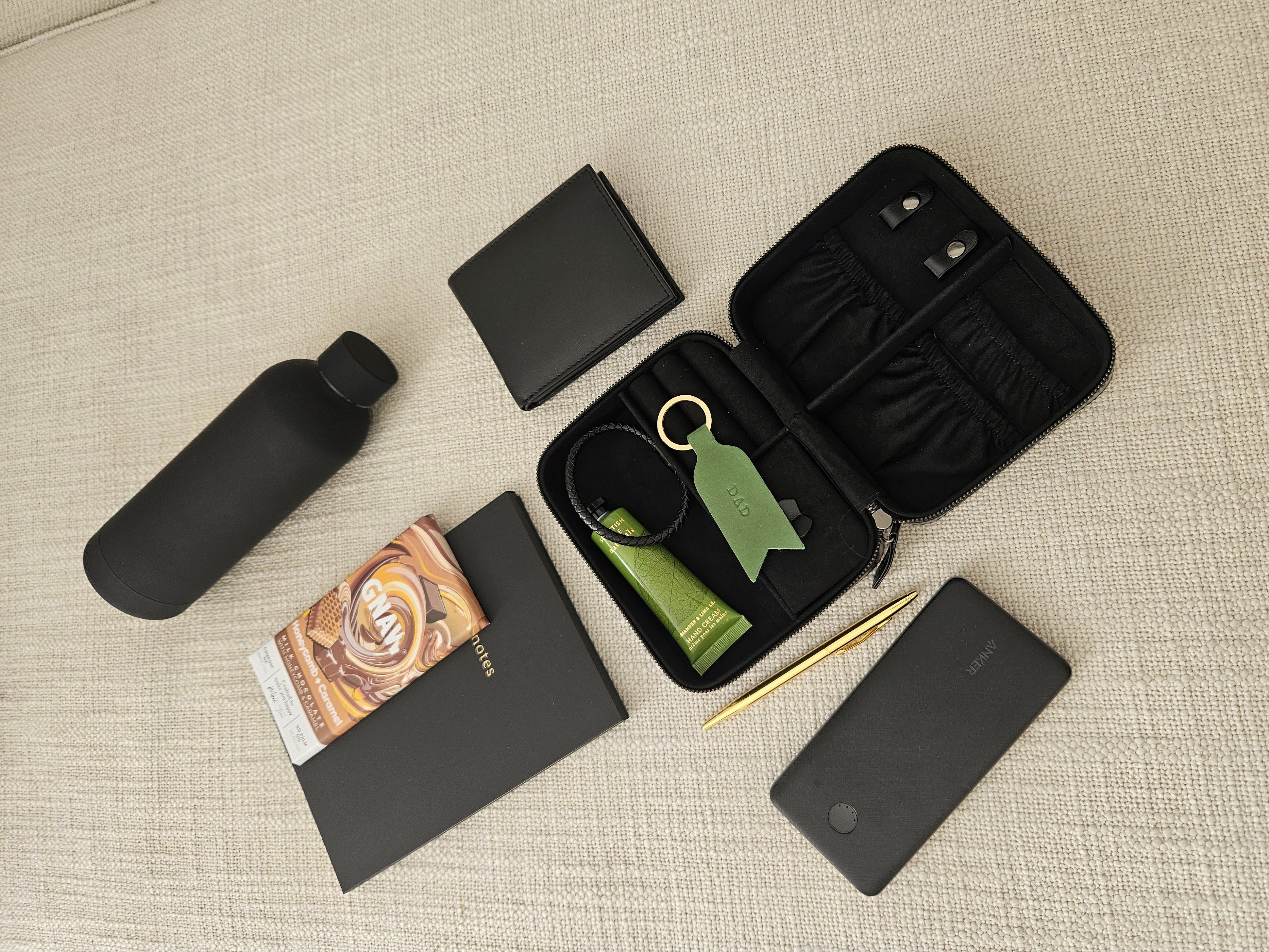 Collection of travel-sized products including a water bottle, phone case, and skincare items on a textured surface.