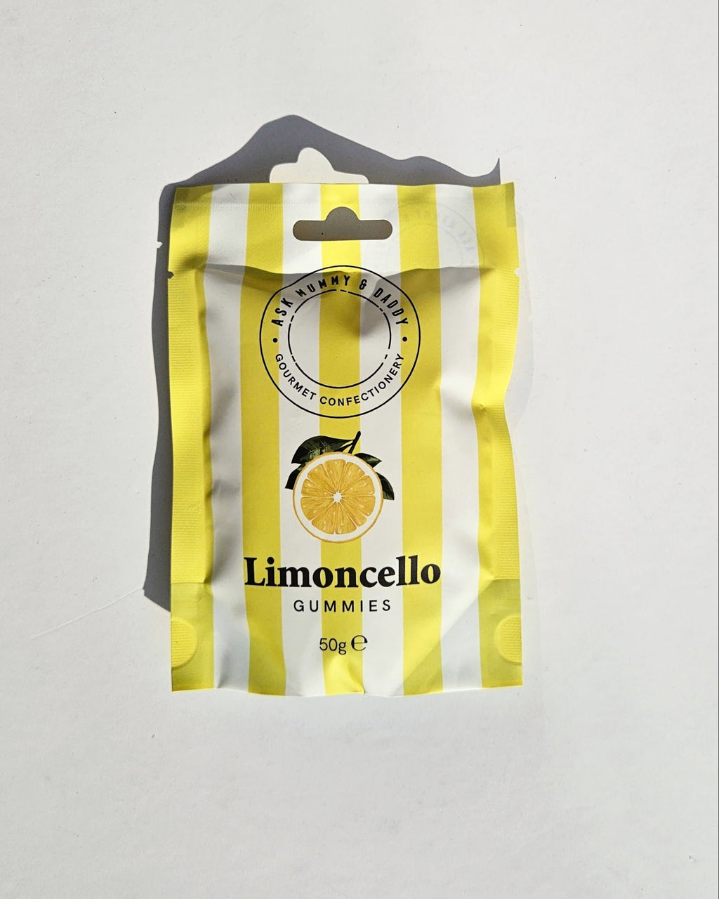 A package of Limoncello Gummies, featuring a yellow and white striped design with a lemon graphic, shown on a light gray background.