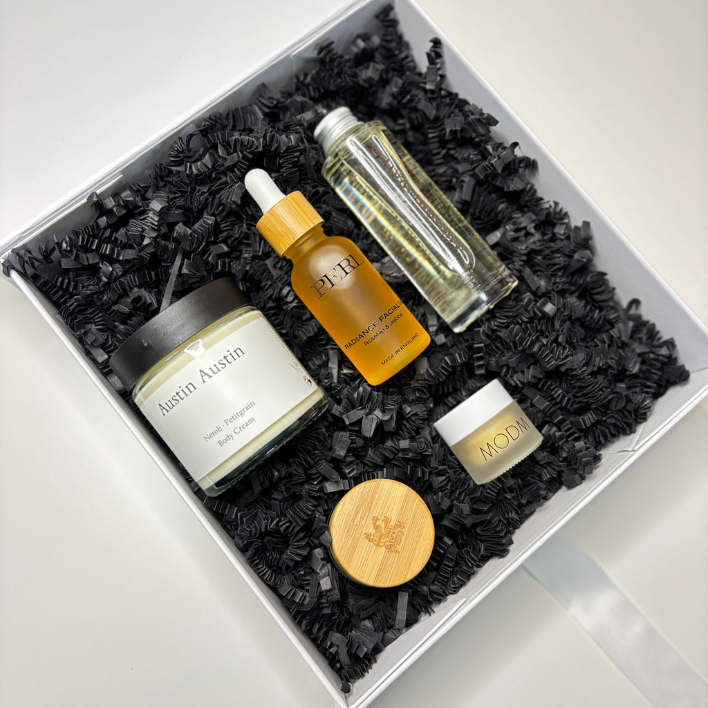 Set of skincare products in a decorative box with black shredded paper on a white background