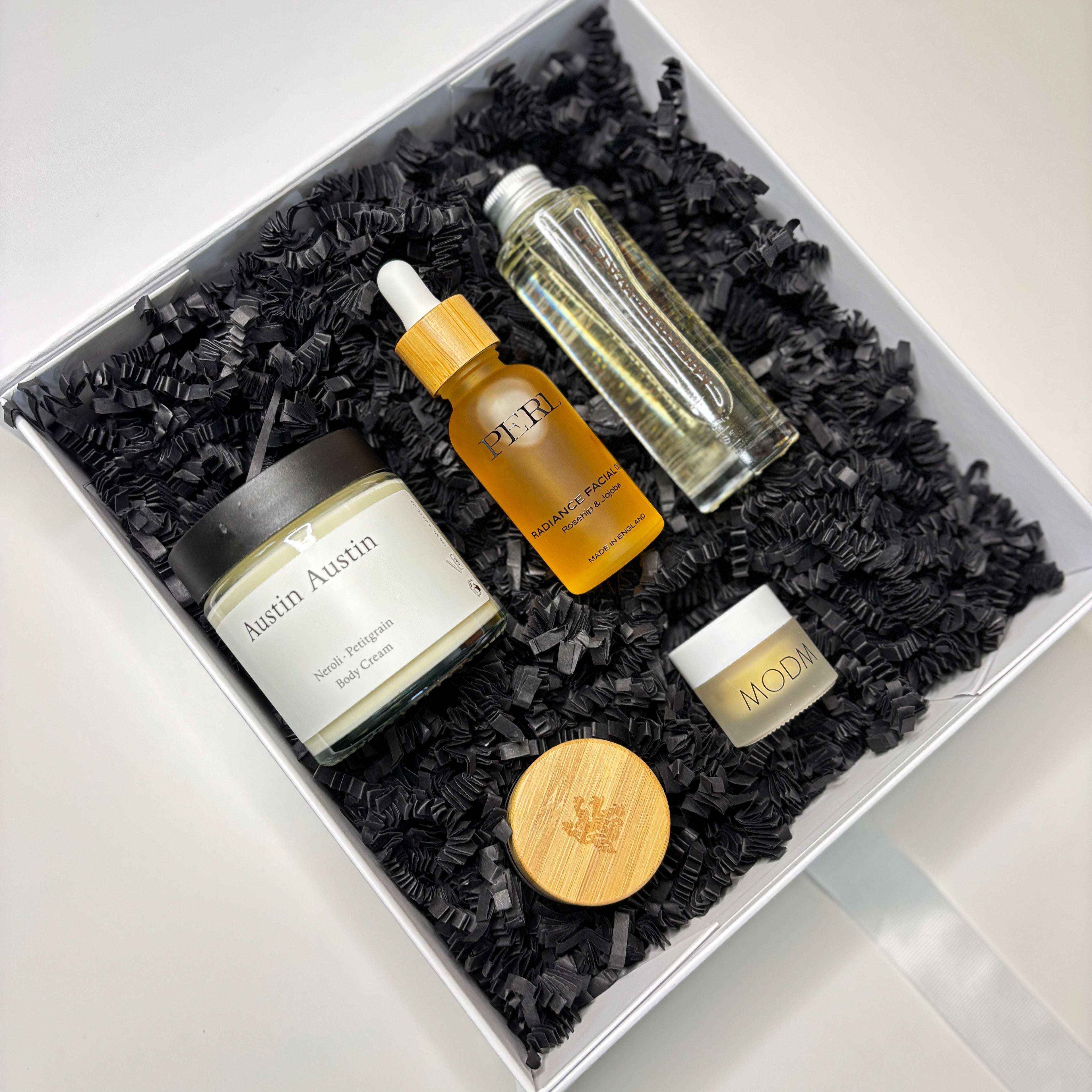 Set of skincare products in a decorative box with black shredded paper on a white background