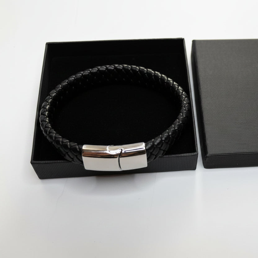 Black leather bracelet with silver clasp in a black box on a light gray background