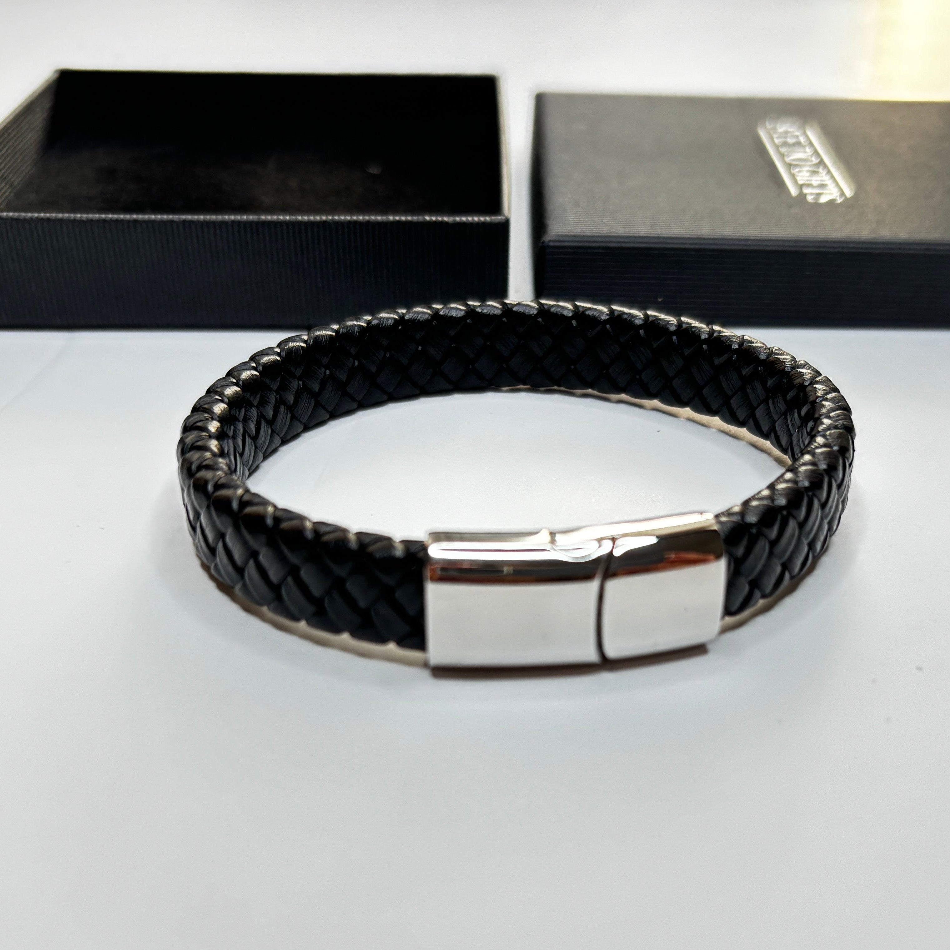 Black braided leather bracelet with silver clasp on a white background