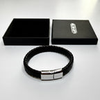 Black braided bracelet with a silver clasp on a white background, featuring a branded box.